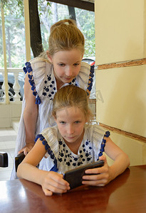 两个双胞胎白人女孩用智能手机 9 年