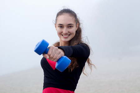 年轻运动女性在健身工作期间用哑铃锻炼