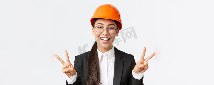 快乐成功的亚洲女工程师、戴安全帽的建筑建筑师和显示和平标志和微笑的卡瓦伊的商务套装的特写，站在白色背景