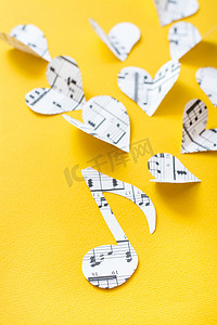 音符、谱号和心从纸上剪下来，黄色背景上有音乐文本。