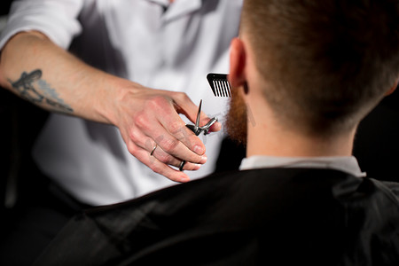 剪头发摄影照片_大师在理发店剪头发和胡子。