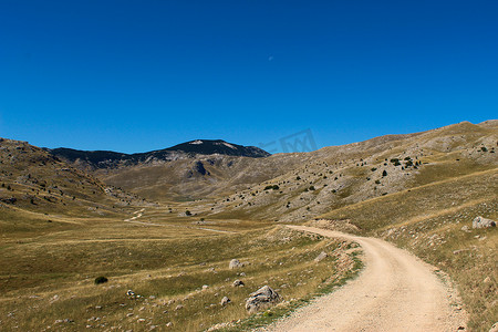 老山路，岩石景观，山顶在蓝天和月亮的背景中。