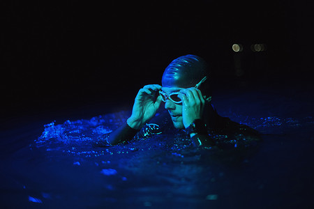真正的铁人三项游泳运动员在夜间霓虹灯下的艰苦训练中休息