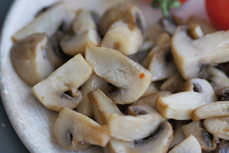 白色背景黑盘上的大蒜和欧芹炒蘑菇