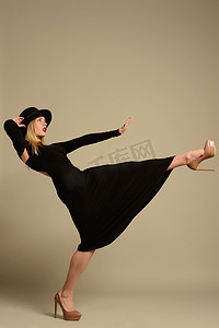 一个戴着黑色帽子，穿着高跟晚礼服的漂亮女孩，带着一股劲风。