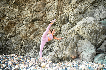 海边女子摄影照片_女子体操运动员正在海边的沙滩上训练。