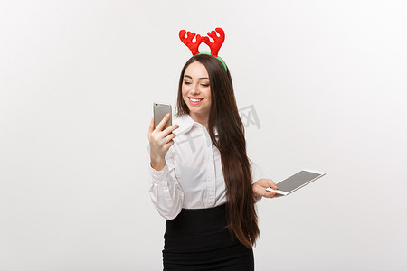 经营理念-圣诞主题的年轻白人女商人用令人惊讶的面部表情玩 moblie 电话。
