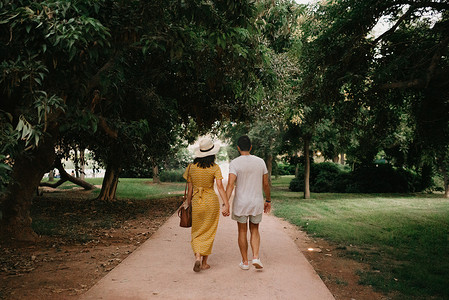 一个女孩和她的男朋友在沙路上行走的背后照片