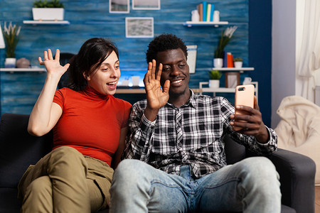 视频通话界面摄影照片_微笑的多民族夫妇在智能手机上挥手