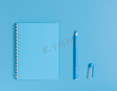 蓝色笔记本和钢笔套装在蓝色桌面背景上，顶部 vie