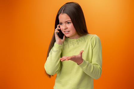 十几岁的女孩在橙色背景下打电话隔离
