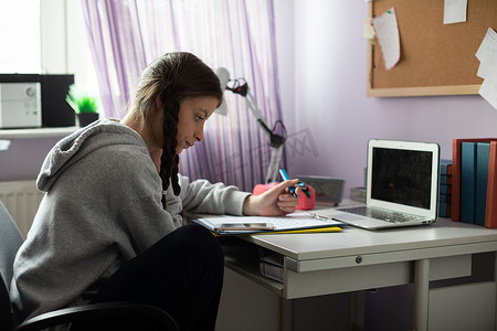 一个学生坐在她的办公桌前做功课。