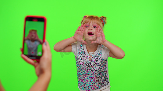 可爱vlog摄影照片_可爱的小女孩博主在手机摄像头前录制视频，享受色度键上的舞蹈内容