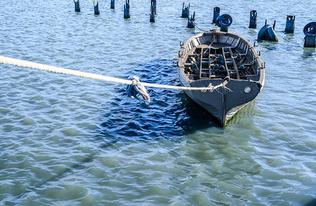 渔船绳子摄影照片_蓝绿色水中用绳子绑着的灰色渔船