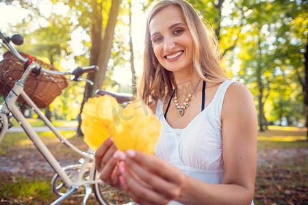 女人停下自行车去收集美丽的秋叶