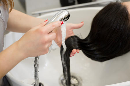 美发师在 spa 沙龙洗头发的女孩。