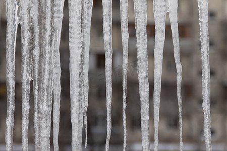 阳台冬天摄影照片_积雪的屋顶上挂着危险的冰柱。