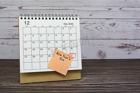 一月历摄影照片_2022 年 12 月的日历在木桌上，日期圈和便利贴上的文字。