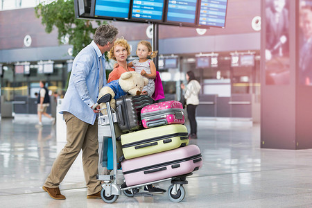 假期旅行的家庭带着镜头光晕在机场散步