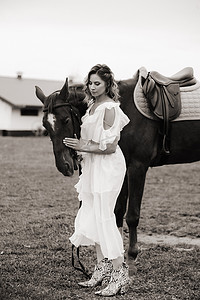 在老牧场的一匹马旁边穿着白色太阳裙的漂亮女孩。