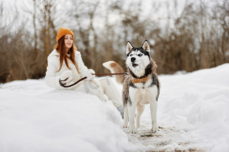 冬天在户外田野里牵着狗散步的年轻女子