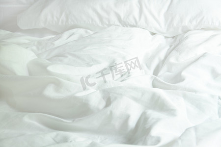 床上的白色枕头和卧室里有皱纹凌乱的毯子，F