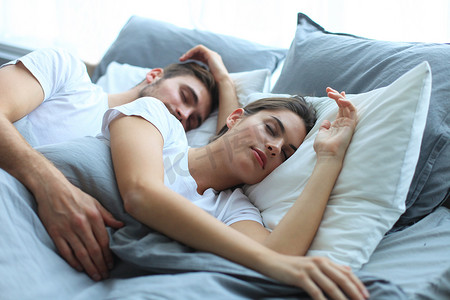 床上摄影照片_幸福的夫妻在家里舒适的床上睡觉。