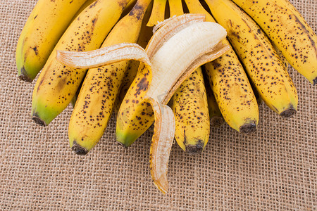 剥皮的香蕉放在一堆黄色雀斑香蕉上