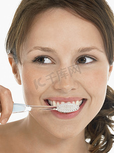 箭头向下动图摄影照片_一名年轻女子在白色背景下刷牙的特写