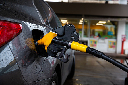 燃油摄影照片_用燃油分配器为汽车加油汽油或柴油，并在加油站支付税款以运输他的旅行