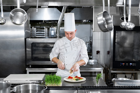 男装饰品摄影照片_男厨师在厨房里装饰食物。