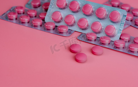 粉红色的药片和粉红色背景的药片泡罩包装。