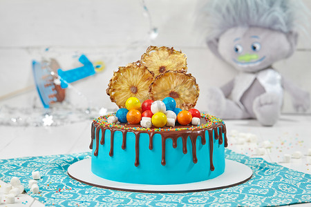 结冰的球摄影照片_蓝色蛋糕，配巧克力糖衣、蜜饯菠萝、五颜六色的口香糖球