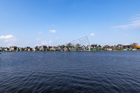 荷兰桑斯安斯风车村，荷兰村庄，春天，平静的运河水反射在水面上，屋顶上有小红色屋顶的温室