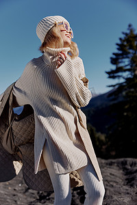 秋装摄影照片_穿着秋装的年轻女子站在岩石蓝天的生活方式上