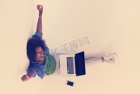 非洲裔美国女性坐在地板上，笔记本电脑俯视