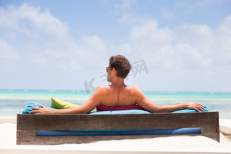 暑假生活免费摄影照片_穿着豪华躺椅的轻松男人在美丽的海滩上享受暑假。