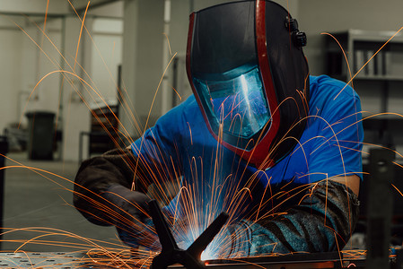 重工业工厂摄影照片_在工厂内工作的专业重工业焊工，戴着头盔并开始焊接。