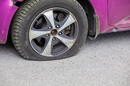 扁平运输摄影照片_灰色沥青表面干燥阳光明媚的民用汽车扁平轮胎特写