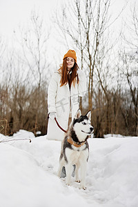 冬天遛狗摄影照片_女人冬天的衣服在雪地里遛狗生活方式