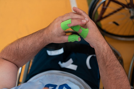一名残疾篮球运动员穿上紧身胸衣，在手臂和手指上缠上绷带，准备在竞技场上进行比赛