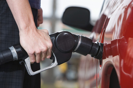 经济物品摄影照片_一名年轻人在加油站给汽车加油的中段