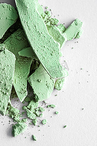 绿色眼影粉作为化妆调色板特写，隔离在白色背景、破碎的化妆品和美容质感中