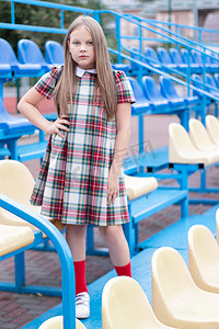 穿着校服的漂亮女孩在学校体育场的蓝色和黄色论坛上。