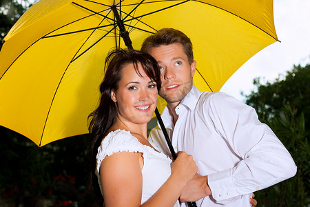 打着雨伞的情侣摄影照片_幸福的情侣在夏天的雨中打着伞