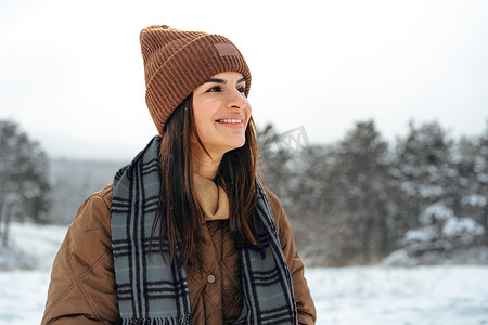 穿着冬季保暖夹克的女人在白雪皑皑的冬季森林中行走
