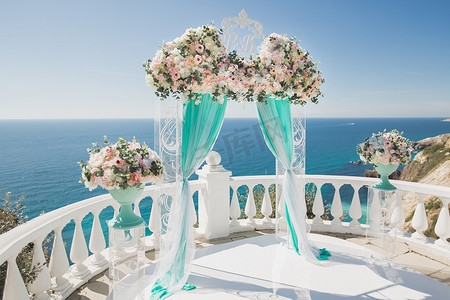 有鲜花的典雅的婚礼拱门，在海洋和蓝天的背景的花瓶