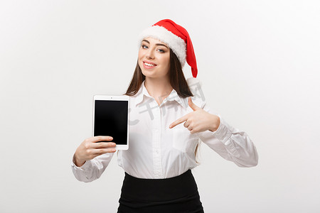 经营理念-圣诞主题中的年轻白人女商人展示并指向数字平板电脑。