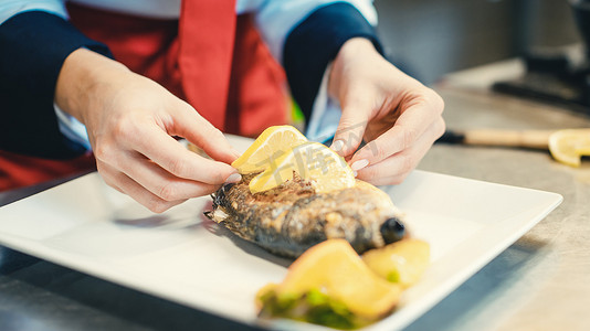 餐厅的主厨将食物放在即将上菜的盘子上