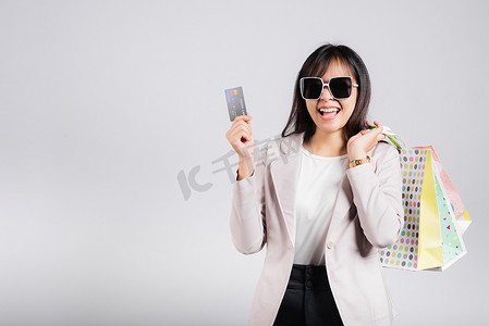 戴眼镜自信购物者微笑的女人手拿网上购物袋和信用卡付款